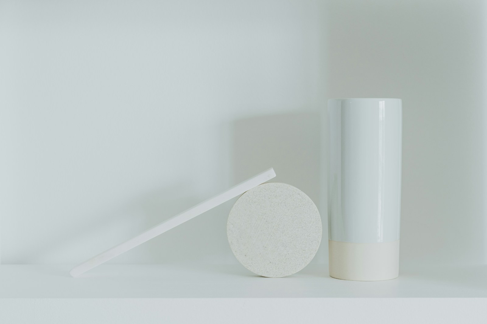 a white vase sitting next to a white round object